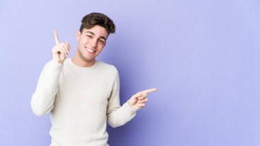 Mor arka planda izole edilmiş genç beyaz adam farklı kopya alanlarını gösteriyor, birini seçiyor, parmağıyla gösteriyor..