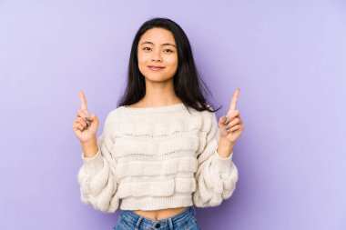 Mor arka planda izole edilmiş genç Çinli kadın iki parmağı da boş bir alan gösteriyor..
