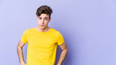 Mor arka planda soyutlanmış, kafası karışmış, şüpheli ve kararsız genç bir beyaz adam..