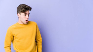 Mor arka planda izole edilmiş genç beyaz adam gördüğü bir şey yüzünden şoka uğruyor..