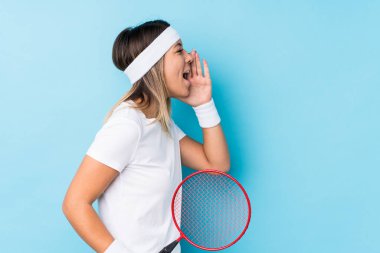 Badminton oynayan beyaz bir kadın bağırıyor ve ağzı açık bir şekilde avucunu tutuyor..