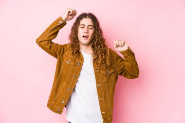 Genç, uzun saçlı bir adam özel bir günü kutluyor, atlıyor ve enerjiyle kollarını kaldırıyor..