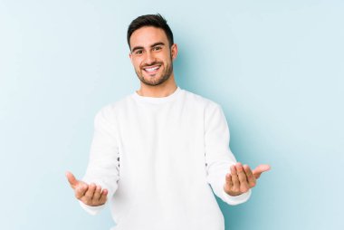 Mavi arka planda izole edilmiş beyaz bir genç hoş bir yüz ifadesi sergiliyor..