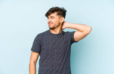 Genç bir Arap erkek, sakin yaşam tarzından dolayı boyun ağrısı çeken mavi bir arka planda izole edilmiş..