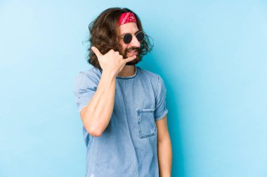 Genç, uzun saçlı, festival hipster 'ı giymiş bir adam izole görünüyor. Cep telefonu hareketini parmaklarıyla gösteriyor..