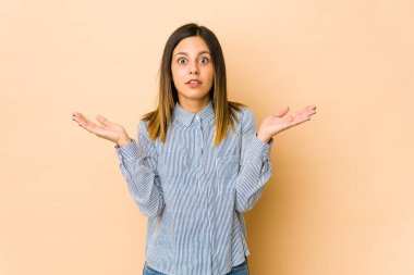 Bej arka planda izole edilmiş genç bir kadın şaşırmış ve şok olmuş..