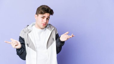 Mor arka planda izole edilmiş genç beyaz adam sorgulama sırasında omuz silkiyor ve şüphe duyuyor..