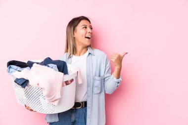 Kirli çamaşırlarını toplayan beyaz bir kadın başparmağıyla işaret ediyor, gülüyor ve kaygısız..