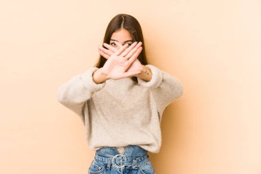 Beyazlı genç bir kadın bej arka planda izole edilmiş bir şekilde inkar jesti yapıyor.