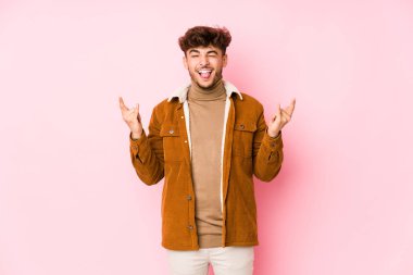 Pembe arka planda yalnız poz veren genç bir Arap. 