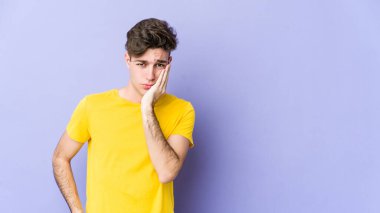 Mor arka planda izole edilmiş genç beyaz adam üzgün ve dalgın hissediyor, kopyalama alanına bakıyor..