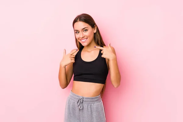 Joven Mujer Atlética Caucásica Posando Fondo Rosa Sonríe Señalando Con — Foto de Stock