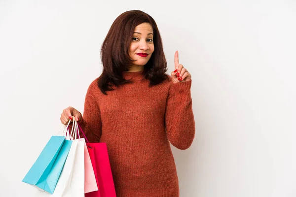 Medelålders Latinamerikansk Kvinna Håller Shoppingpåse Isolerad Visar Nummer Ett Med — Stockfoto