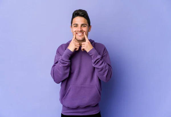 Young caucasian man isolated on purple background doubting between two options.