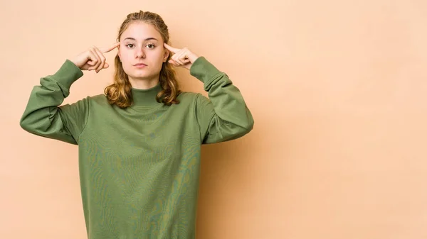 Junge Kaukasierin Isoliert Auf Beigem Hintergrund Konzentriert Auf Eine Aufgabe — Stockfoto