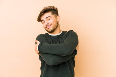 Genç Arap bir adam bej bir arka planda izole edilmiş, güler yüzlü ve mutlu..