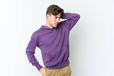 Beyaz arka planda izole edilmiş genç beyaz bir adam yorgun ve uykulu bir şekilde elini başının üstünde tutuyor..