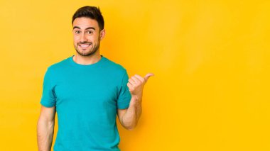 Sarı fırında izole edilmiş genç beyaz adam işaret parmağıyla fotokopi alanını işaret ederek şok oldu..