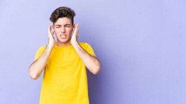 Genç beyaz adam mor arka planda izole edilmiş parmaklarıyla kulaklarını kapatıyor, gürültülü bir ortam tarafından stresli ve umutsuz..