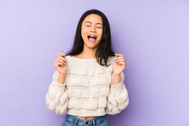 Genç Çinli bir kadın, mor bir arka planda izole edilmiş neşeli bir şekilde gülüyor. Mutluluk kavramı.