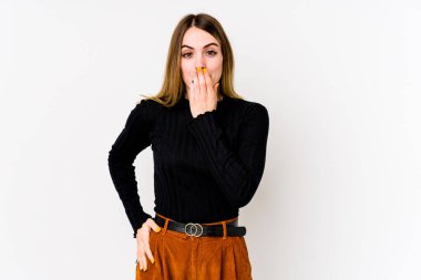Beyaz arka planda izole edilmiş genç beyaz kadın şok olmuş, elleri ağızda, yeni bir şey keşfetmeye hevesli..