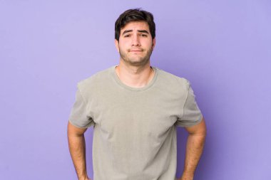 Mor arka planda izole edilmiş genç bir adam üzgün, ciddi bir yüz, sefil ve hoşnutsuz hissediyor..