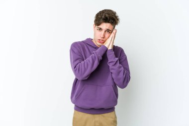 Beyaz arka planda izole edilmiş genç beyaz adam esniyor. Ağzı eliyle kapatan yorgun bir hareket sergiliyor..