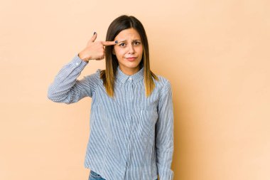 Bej arka planda izole edilmiş genç bir kadın işaret parmağıyla hayal kırıklığı gösteriyor..