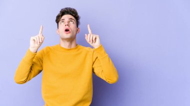 Mor arka planda izole edilmiş beyaz bir adam ağzı açık bir şekilde üst tarafı işaret ediyor..