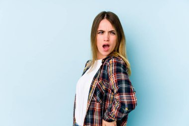 Mavi arka planda izole edilmiş beyaz bir kadın sırt ağrısı çekiyor..