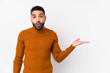 Beyaz arka planı olan genç Latin bir adam, avuç içi fotokopi alanı tutmaktan etkilenmiş..