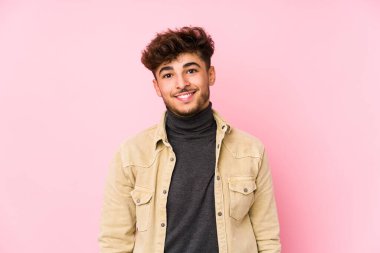 Arka planda poz veren genç Arap adam mutlu, güler yüzlü ve neşeli..
