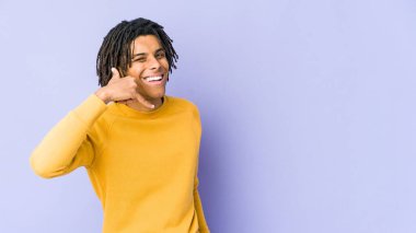 Rasta saç stili giyen genç siyahi adam cep telefonu hareketini parmaklarıyla gösteriyor..