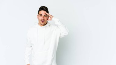 Beyaz arka planda izole genç beyaz adam yüksek sesle bağırıyor, gözleri açık ve elleri gergin tutuyor..