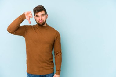 Mavi arka planda izole edilmiş genç beyaz bir adam hoşlanmadığı bir jest yapıyor. Anlaşmazlık konsepti.