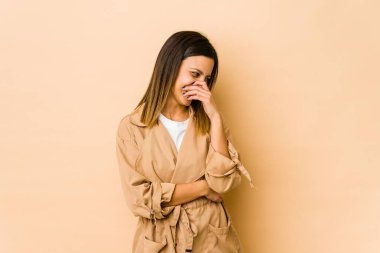 Bej arka planda izole edilmiş genç bir kadın gülüyor, kaygısız, doğal bir duygu..