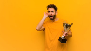 Elinde kupa tutan genç adam bir dedikoduyu dinlemeye çalış.