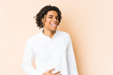 Genç Afrikalı Amerikalı Rasta adam karnına dokunuyor, nazikçe gülümsüyor, yemek yiyor ve tatmin oluyor..