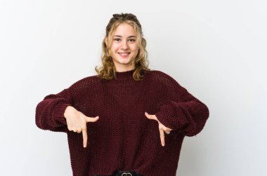 Beyaz arka plandaki genç beyaz kadın parmaklarıyla aşağı işaret ediyor, olumlu bir his..