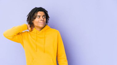 Genç Afrikalı Amerikalı Rasta adam kafasının arkasına dokunuyor, düşünüyor ve bir seçim yapıyor..