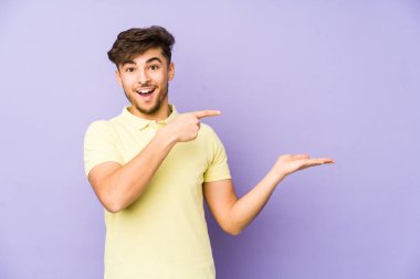 Mor arka planda izole edilmiş genç bir Arap, palmiye üzerinde bir fotokopi alanı tutarken heyecanlanıyor..