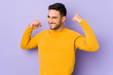 Mor arka planda izole genç beyaz adam özel bir günü kutluyor, atlıyor ve enerjiyle kollarını kaldırıyor..