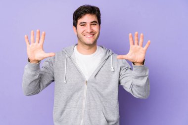 Mor arka planda izole edilmiş genç adam on numarayı elleriyle gösteriyor..