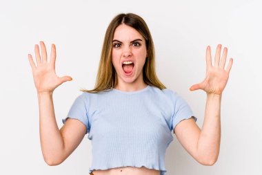 Beyaz arka planda izole edilmiş genç beyaz kadın gökyüzüne haykırıyor, yukarı bakıyor, hayal kırıklığına uğramış..