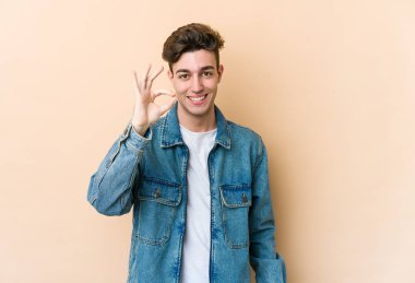 Beyaz tenli genç adam bej arka planda izole edildi. Neşeli ve kendinden emin..