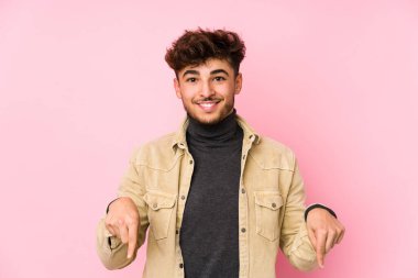 Arka planda poz veren genç Arap bir adam parmaklarıyla aşağıdaki izole noktaları gösteriyor, olumlu bir his..