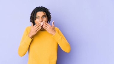 Rasta saç stili giyen genç siyah adam elleriyle ağzını kapatırken şok oldu..