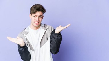 Mor arka planda izole edilmiş genç beyaz bir adam. Kafası karışmış ve omuz silkiyor. Kopya alanını tutmak için..