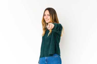 Beyaz arka planda izole edilmiş genç beyaz kadın parmaklarıyla ön tarafı işaret ediyor..