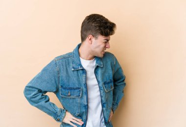 Bej arka planda izole edilmiş beyaz bir adam sırt ağrısı çekiyor..